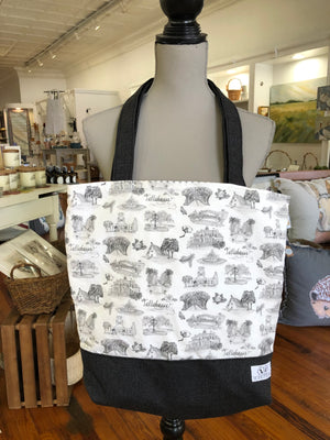 Open image in slideshow, Pictured is a Toile of Tallahassee tote bag hanging from the neck of a mannequin. The tote is made of Toile of Tallahasse black and white fabric except for the base and handles of the bag, which are made of black fabric.
