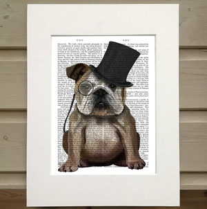 Pictured is a page out of a book framed with a mat. Printed over the page is the image of a cute bulldog wearing a monocle and a tophat. This is an Animal Book Print by FabFunky Ltd sold at The Hare & The Hart.