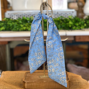 Pictured is Liberty London Hair Scarf in the pattern Blue Capel sold at The Hare & The Hart in downtown Thomasville, Georgia. It is a scarf made from a blue and white fabric.
