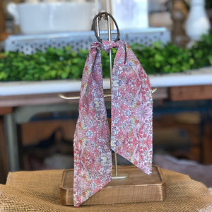 Pictured is Liberty London Hair Scarf in the pattern Strawberry Thief sold at The Hare & The Hart in downtown Thomasville, Georgia. It is a scarf made from pink and blue floral fabric.