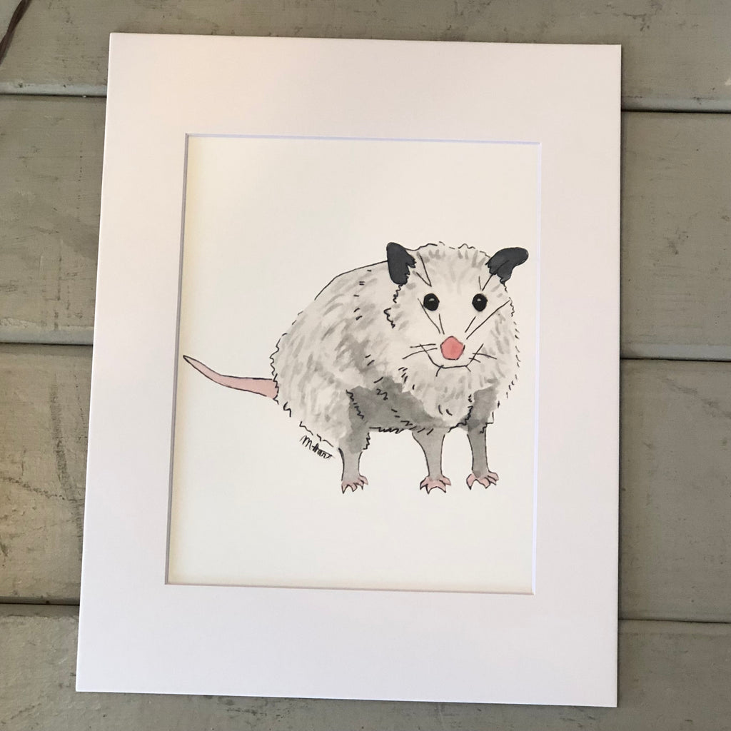 Pictured is a print designed by artist Maddie Hart and sold at The Hare & The Hart in downtown Thomasville, Georgia. It is an 8" x 10", matted to 11" x 14", print of a watercolor possum.