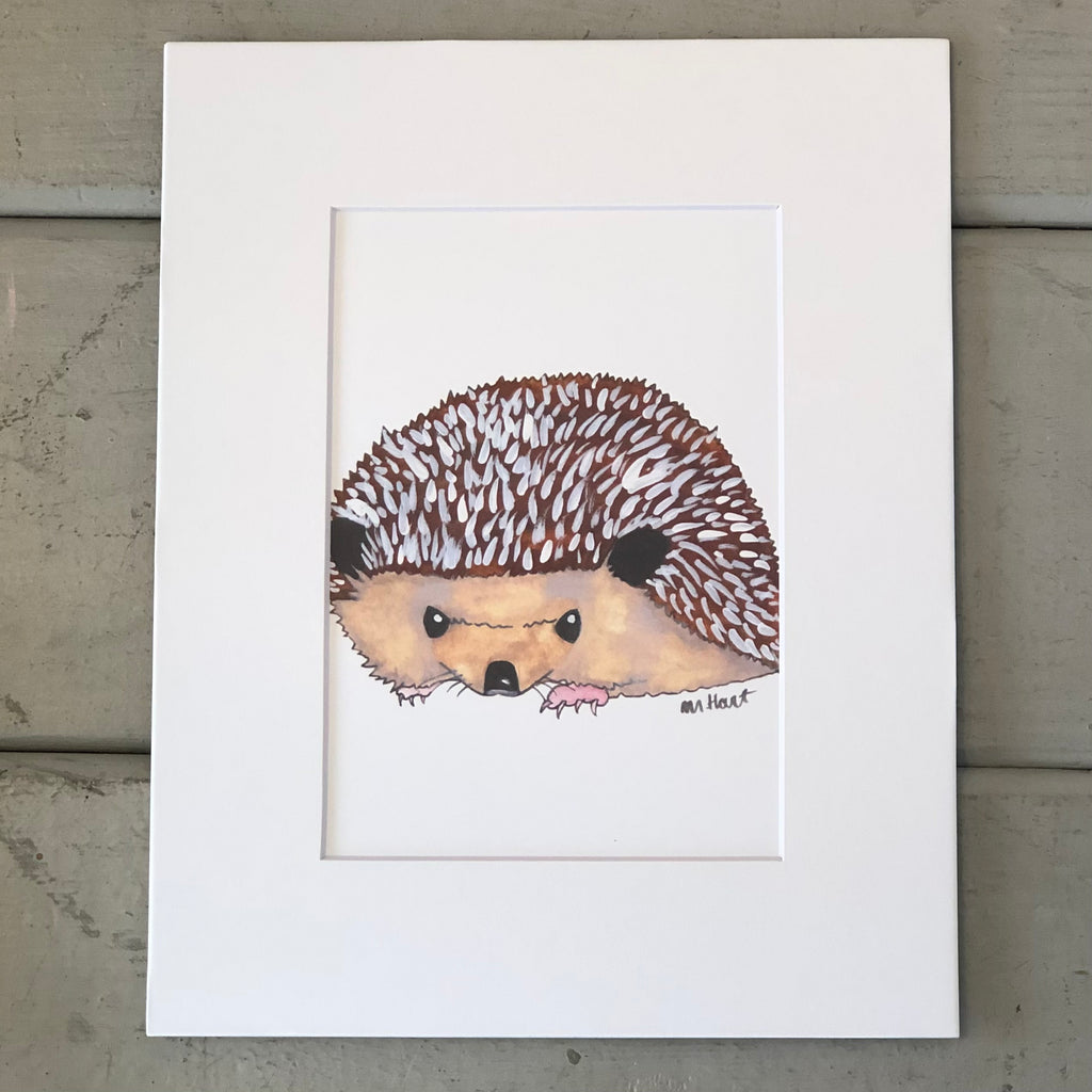 Pictured is a print designed by artist Maddie Hart and sold at The Hare & The Hart in downtown Thomasville, Georgia. It is an 5" x 7", matted to 8" x 10", print of a watercolor hedgehog.