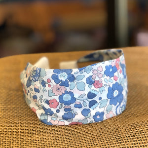 Pictured is Liberty London Flat Headband in the pattern Betsy Blue sold at The Hare & The Hart in downtown Thomasville, Georgia. It is a headband made from blue, pink, and white floral fabric.