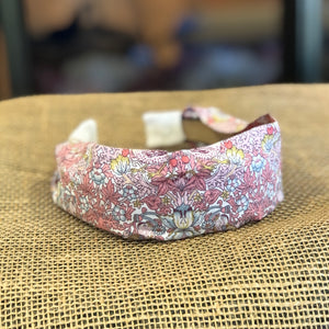 Pictured is Liberty London Flat Headband in the pattern Strawberry Thief Pink sold at The Hare & The Hart in downtown Thomasville, Georgia. It is a headband made from pink and blue floral fabric.