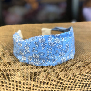 Pictured is Liberty London Flat Headband in the pattern Blue Capel sold at The Hare & The Hart in downtown Thomasville, Georgia. It is a headband made from blue and white floral fabric.