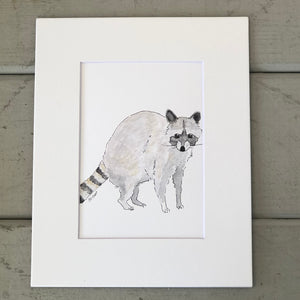Pictured is a print designed by artist Maddie Hart and sold at The Hare & The Hart in downtown Thomasville, Georgia. It is an 5" x 7", matted to 8" x 10", print of a watercolor raccoon.