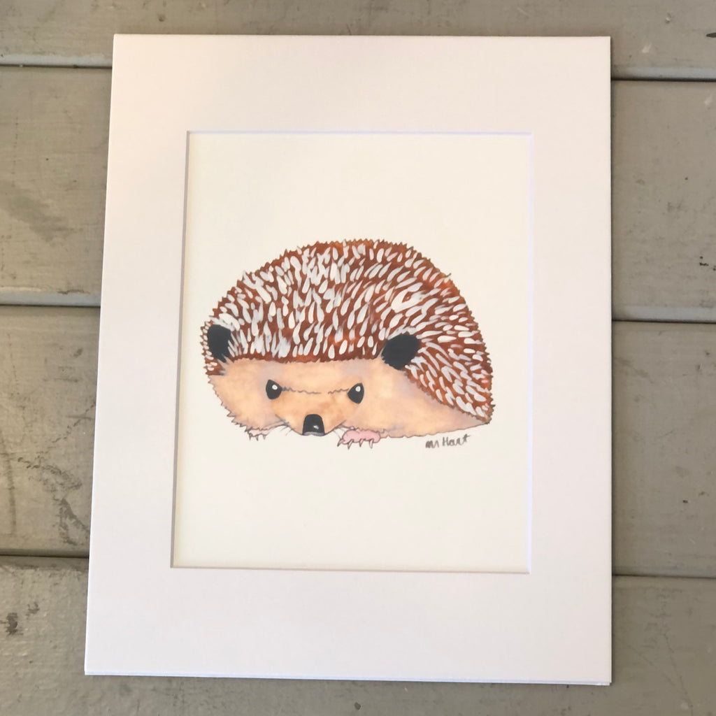 Pictured is a print designed by artist Maddie Hart sold at The Hare & The Hart in downtown Thomasville, Georgia. It is an 8" x 10", matted to 11" x 14", print of a watercolor hedgehog.