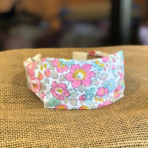 Pictured is Liberty London Flat Headband in the pattern Betsy Pink sold at The Hare & The Hart in downtown Thomasville, Georgia. It is a headband made from pink, blue, green, and white floral fabric.