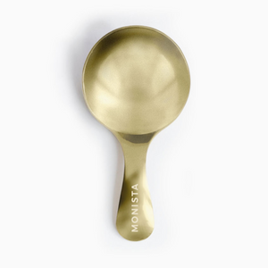 Pictured is a Canister Teaspoon by Monista Tea Company sold at The Hare & The Hart in downtown Thomasville, Georgia. It is a bronze, wide and shallow teaspoon with "MONISTA" printed on the handle.