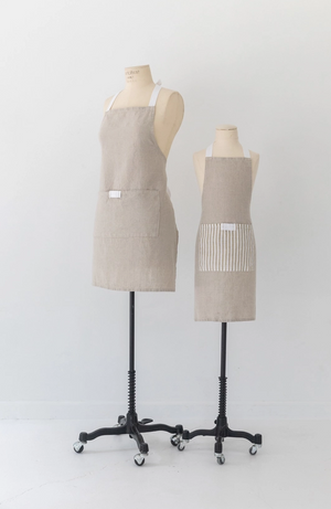 Open image in slideshow, Pictured is the Keepsake Jar Linen Adult Bistro Apron in Oatmeal by Heirloomed Collection sold at The Hare &amp; The Hart in Thomasville, Georgia. There are two apron pictured on two different mannequins, one adult sized and one child sized.
