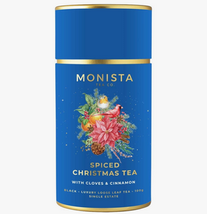 Pictured is a cannister of Monista Tea Co. Spiced Christmsa Tea. The container is blue with gold accents and a Christmas bouquet design in the center.