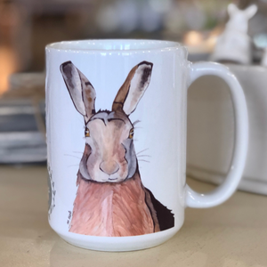 Pictured is a white coffee mug with a watercolor design of a hare on it.