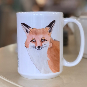 Pictured is a white coffee mug with a watercolor design of a fox on it.