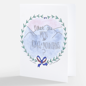 Pictured is a notecard with watercolor artwork by the artist Maddie Hart printed on the front of it. It is sold at The Hare & The Hart in downtown Thomasville, Georgia. The artwork is of mountains surrounded by a wreath and it reads "What are MEN to ROCKS & MOUNTAINS? Jane Austen Pride and Prejudice"