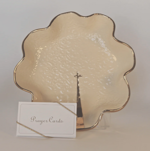 Pictured is The Petite Goldie by PrayerBowl sold at The Hare & The Hart in downtown Thomasville, Georgia. It is a cream colored ceramic bowl with a gold, fluted edge and a gold cross in the center.
