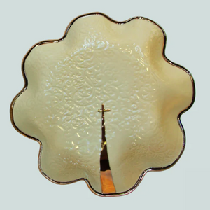 Pictured is The Goldie by PrayerBowl sold at The Hare & The Hart in downtown Thomasville, Georgia. It is a cream colored ceramic bowl with a gold, fluted edge and a gold cross in the center.