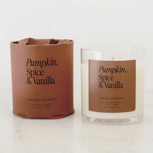 Pictured is Pumpkin, Spice, and Vanilla Fall Candle by Heirloomed Collection sold at The Hare & The Hart in downtown Thomasville, Georgia. It is a white candle in clear glass with a brown label that says, "Pumpkin, Spice, & Vanilla HEIRLOOMED SOY WAX CANDLE 8 oz / 227g ATLANTA, GA"