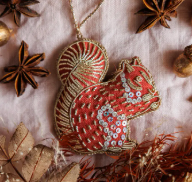 Pictured is Handmade Irish Linen Squirrel Ornament sold at The Hare & The Hart in downtown Thomasville, Georgia. It is an orange ornament in the shape of a squirrel.