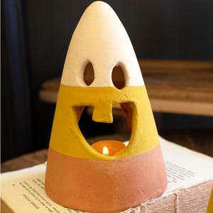 Pictured is a Terracotta Candy Corn Jack-o-Lantern Lantern sold at The Hare & The Hart in downtown Thomasville, Georgia. It is a candy corn-shaped terracotta decoration with a jack-o-lanetern face in candy corn colors.