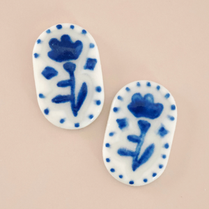 Pictured is James Folk Stud Earrings sold at The Hare & The Hart in downtown Thomasville, Georgia. They are white ceramic earrings with painted on blue flowers and dots.