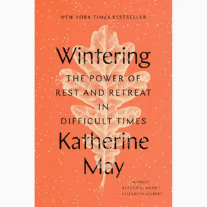 Pictured is the book "Wintering" by Katherine May sold at The Hare & The Hart in downtown Thomasville, Georgia. The cover is orange with a white leaf illustration. The full title reads, "Wintering: The Power of Rest and Retreat in Difficult Times". A review on the cover reads, "'A truly beautiful book.' - Elizabeth Gilbert"