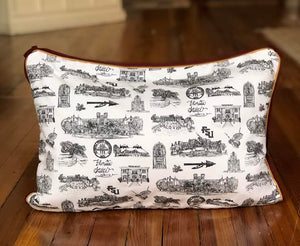 There is a lumbar pillow covered with Toile of FSU fabric. The Toile of FSU pattern is black and white. The border of the pillow is garnet and gold piping.