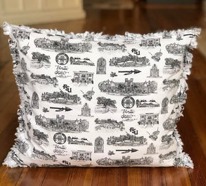 Pictured is a square pillow covered with Toile of FSU black and white patterned fabric. The edges of the pillow are frayed.