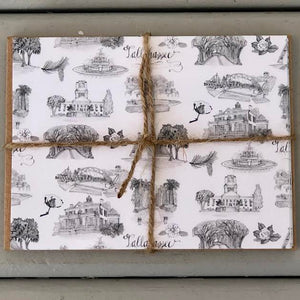 There is a stack of notecards with the black and whtie Toile of Tallahassee pattern on their covers and a stack of brown envelopes  tied together with twine.