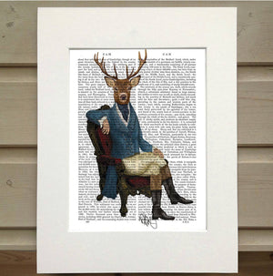 Pictured is a page from a book. Printed onto the page is a man lounging in a chair. He is dressed in old fashioned hunting clothes. He sits in an ornate chair. Instead of the head and face of a man, he has a deer head. This is an Animal Book Print sold at The Hare & the Hart.