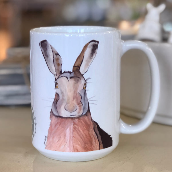 Pictured is a white coffe mug with a watercolor design of a hare on it.
