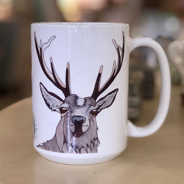 Pictured is a white coffe mug with a watercolor design of a hart on it.