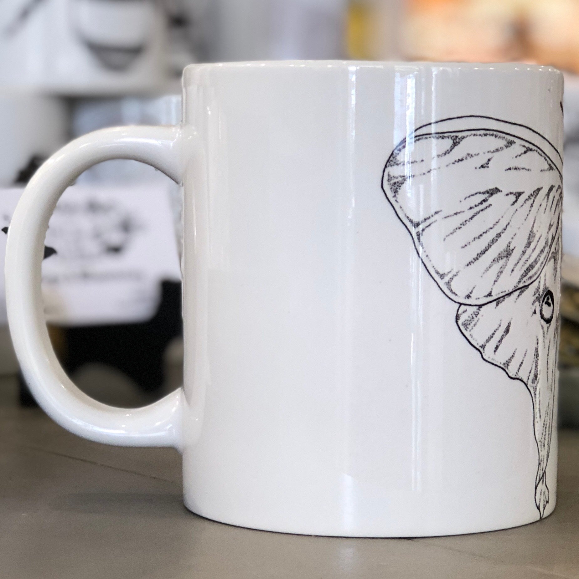A large white mug with a black luna moth design pictured from the side. This is a Large Mug by Birds & Bees sold at The Hare & The Hart.