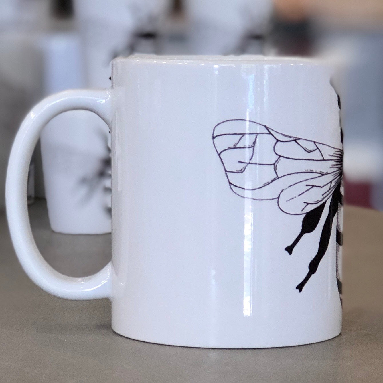 A large white mug with a black bee design pictured from the side. This is a Large Mug by Birds & Bees sold at The Hare & The Hart.