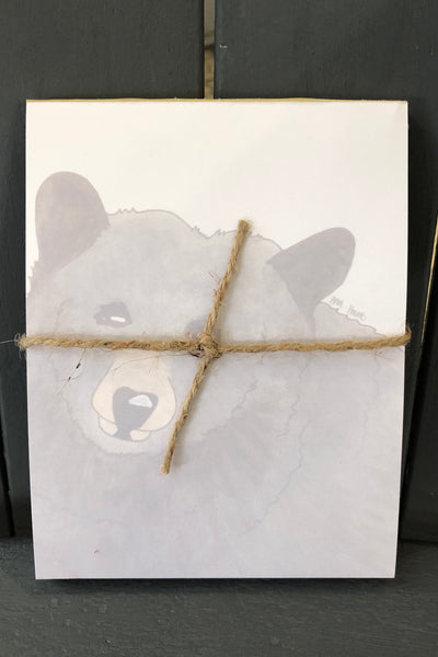 There is a notepad tied together with twice. The paper of the notepad is printed with a design of a bear.