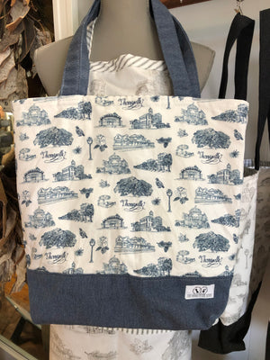 There is a Toile of Thomasville tote in blue and white fabric. The bottom and handles of the bag are blue fabric.