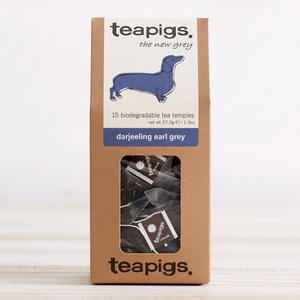 PIctured is the packaging for Teapigs Darjeeling Earl Grey tea. It is a brown box with a clear plastic window in the front showing the teabags that are inside. The label on the box is white with a purple daschund. The label reads "teapigs the new grey 15 biodegradable tea temples darjeeling earl grey."