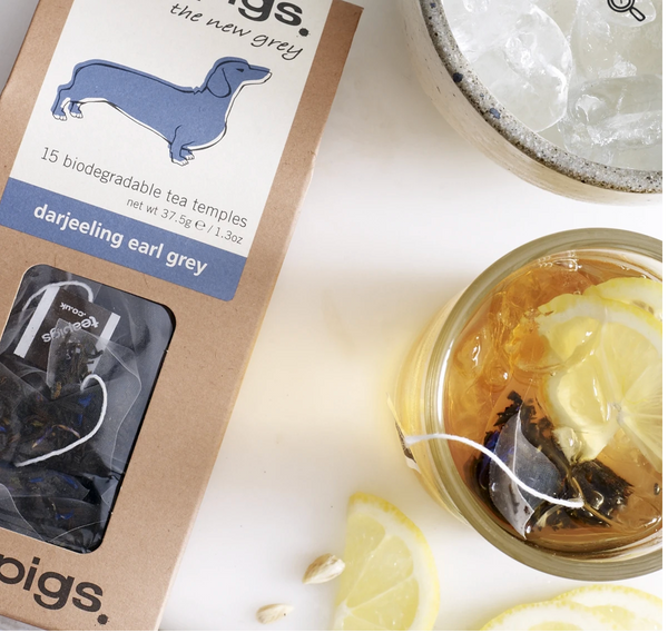 Pictured from above is the packaging for Teapigs Darjeeling Earl Grey next to a cup of tea.