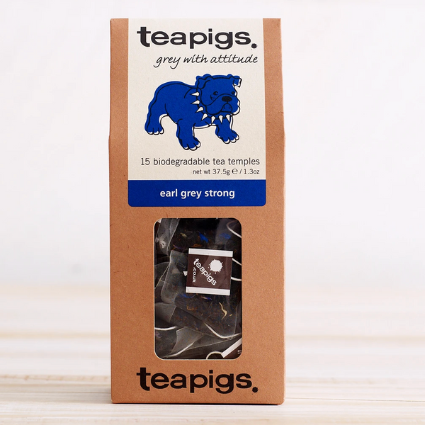 Pictured is the packaging for Teapigs Earl Grey Strong tea. The box is brown with a clear plastic window that shows the teabags inside. The label is white with a blue bulldog and has the words "teapigs grey with attitude 15 biodegradable tea temples earl grey strong."