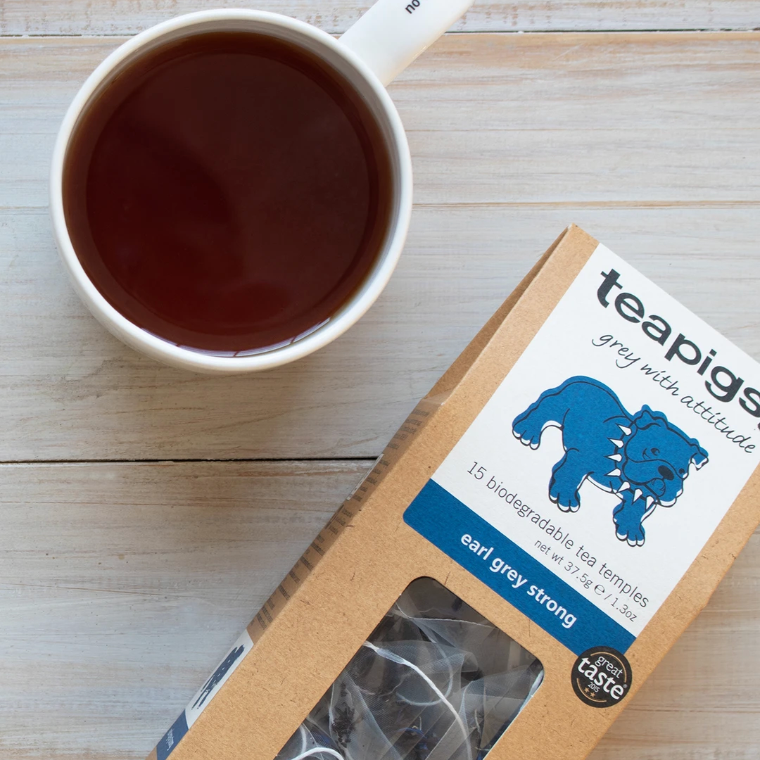 Pictured from above is a package of Teapigs Earl Grey Strong tea. Next to it a mug of tea.