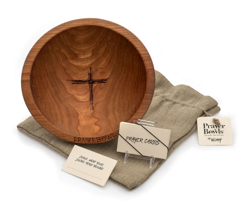 Pictured is the Noah Prayer Bowl displayed on top of its burlap sack packaging. Next to it is a stack of the prayer cards that come with it.
