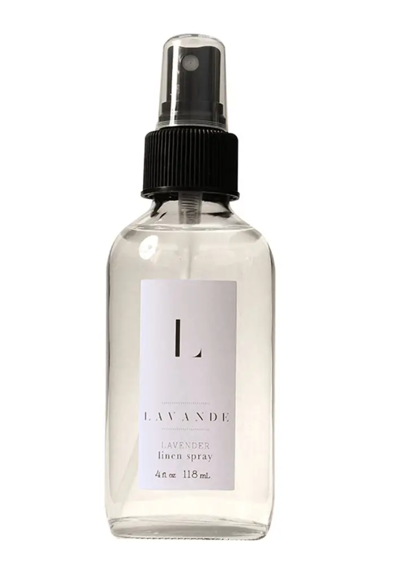 Pictured is a glass spray bottle of Lavande Linen Spray. The liquid inside is clear. The bottle has a white Lavande label sticker on it.