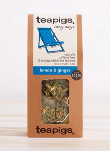 Pictured is the packaging for lemon & ginger Teapigs tea. It has a clear plastic window to display the teabags inside. The label is white with a blue beach chair and the words "teapigs lazy days naturally caffeine free 2 biodegradable tea temples lemon & ginger"