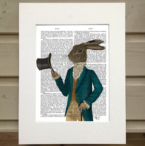 A page from a book is framed with mat. Printed over the page is a figure wearing an old fashioned outfit. He wears a turquoise coat, a mustard vest, a white turtleneck poufy shirt, and kahki pants. The figure has the head of a hare rather than the head of a man. He holds a tophat as if he's tipping it toward the viewer. In his other hand is a cane.