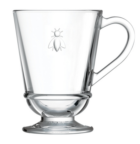 A glass coffee mug with a bee embossed on it. It is cylindrical in shape. There is a Bee Coffee Mug by La Rochere sold at The Hare & The Hart.