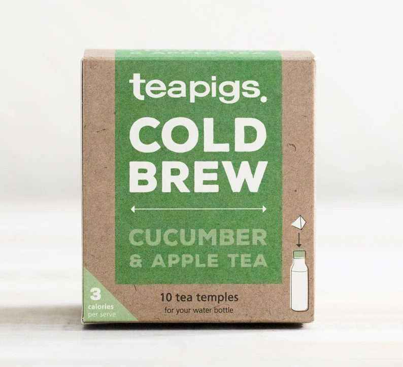 Pictured is the packaging for Teapigs Cold Brew Cucumber and Apple tea. It is a brown box with a green label that reads "teapigs COLD BREW CUCUMBER & APPLE TEA," "10 tea temples for your water bottle." There is a drawing of a water bottle with an arrow pointing a teabag toward the bottle's lid.