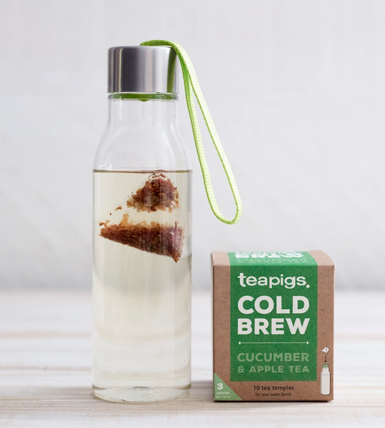Pictured is a clear reusable water bottle with water and a teabag inside of it. There is a package of Teapigs Cold Brew Cucumber and Apple next to it.
