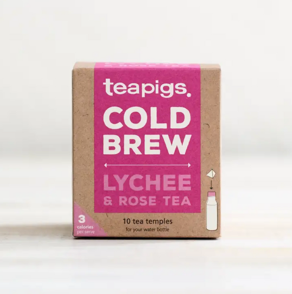 Pictured is the packaging for Teapigs Cold Brew Lychee and Rose tea. It is a square brown box with a pink label that reads "teapigs COLD BREW LYCHEE & ROSE TEA," "10 tea temples for your water bottle." It also has an illustration of a teabag with an arrow pointing to the lid of a water bottle and a pink triangle in the corner that reads "3 calories per serving."