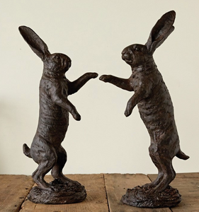 Pictured are two Fighting Hares Statues by Creative Co-op sold at The Hare & The Hart. They are facing each other with their front legs up in the air, about to strike. They are positioned on their hind legs and have their ears pointed up into the air.