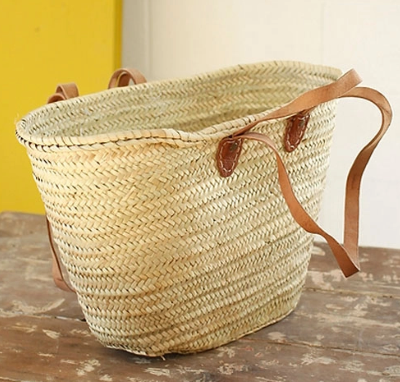 This is a Double Handled French Market Basket by Medina Mercantile and sold at The Hare & The Hart. The basket is in the shape of a tote bag and is light in color. There are four handles on the basket in total- two on each side. There is one small handle and one long handle on each side of the basket.