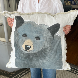 Pictured is a Bear Appliquéd Pillow Cover 26" x 26" being held by a woman. It's sold at The Hare & The Hart in downtown Thomasville, Georgia.